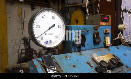 Manometer auf dem Bedienfeld. Das Manometer oder die Druckanzeige steht auf dem alten blauen Bedienfeld, das über den Schlüssel funktioniert. Stockfoto