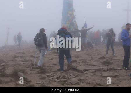 Peak Hoverla/Ukraine - Touristen mit Kindern klettern im starken Nebel auf den Gipfel des Berges. Die Spitze des Berges ist mit Wolken bedeckt Stockfoto