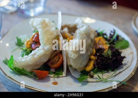 Köstlicher Fischtaco auf einem weißen Teller mit Salatbeschnitt. Stockfoto