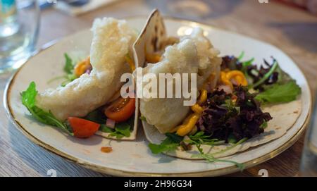 Köstlicher Fischtaco auf einem weißen Teller mit Salatbeschnitt. Stockfoto