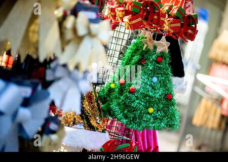 Delmenhorst, Deutschland. 04th Dez 2021. Verschiedene Weihnachtsartikel, darunter grüne Weihnachtsmützen, stehen vor einem Geschäft in der Innenstadt zum Verkauf. Das Weihnachtsgeschäft in den niedersächsischen Innenstädten ist auch in diesem Jahr wieder von einer schweren Corona-Delle bedroht. Quelle: Hauke-Christian Dittrich/dpa/Alamy Live News Stockfoto