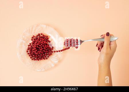 Essen Weihnachten Konzept des neuen Jahres rote Perlen Dekoration wie Spaghetti. Kreative Pasta-Mahlzeit für den Urlaub auf pastellfarbenem Hintergrund. Flach liegend. Stockfoto