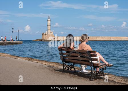 Zwei Frauen sitzen auf einer Bank im venezianischen Hafen von Chania, Kreta, Griechenland, 18. Oktober 2021 Stockfoto