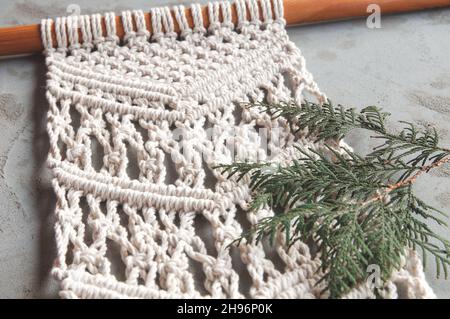 Macrame handgemachte Macrame-Textur. Einrichtung mit Baumwollkordel und Macrame. Umweltfreundliche moderne Strickmode. DIY natürliches Dekor Konzept. Stockfoto