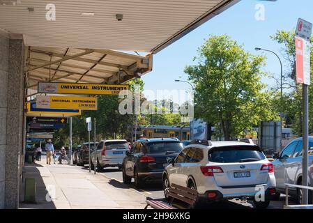 Mit der T1 North Shore Bahnlinie und dem Pacific Highway im Hintergrund, laufen die Menschen den Fußweg vor den Geschäften im Vorort Lindfield entlang Stockfoto