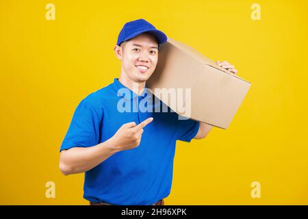Portrait aufgeregt Lieferung glücklich Mann logistischen stehend er lächeln in blauen T-Shirt und Mütze Uniform halten Paketkasten zeigt Finger auf die Box, stu Stockfoto
