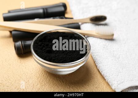 Schale mit aktivem Holzkohle-Zahnpulver auf beigem Hintergrund Stockfoto