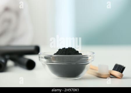 Schüssel mit aktivem Holzkohle-Zahnpulver und Bürsten auf dem Tisch Stockfoto