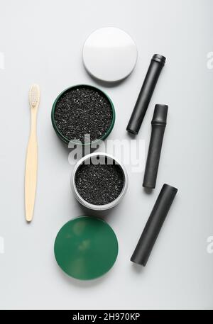 Gläser mit aktivem Holzkohle-Zahnpulver, Pinsel und Bambusstäbchen auf hellem Hintergrund Stockfoto
