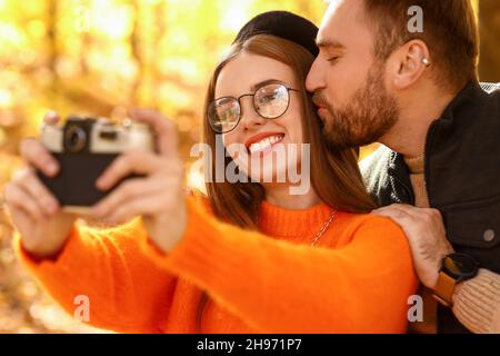 Liebevolles Paar, das im Herbstpark fotografiert Stockfoto