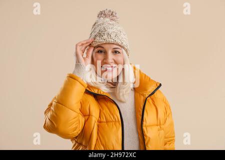 Schöne reife Frau in Winterkleidung auf farbigem Hintergrund Stockfoto