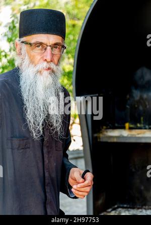 Danilovgrad Kommune, Montenegro-September 13th 2019: Im Kloster Ostrog steht ein Mann in traditioneller orthodoxer Mönchskleide am Eingang der Kirche Stockfoto