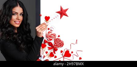 Frau mit Zauberstab in der Nähe von Valentines Tag Dekoration und herzförmige Lollis auf weißem Hintergrund Stockfoto