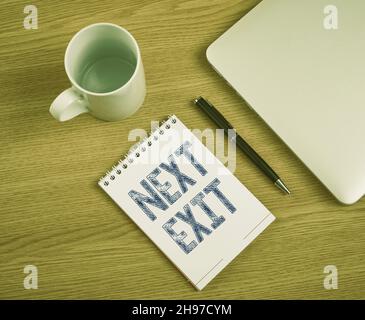 Schild mit der Anzeige „Nächster Ausgang“. Geschäftsansatz der folgende Ausweg oder Akt des Ablegehens an einem Ort oder auf der Autobahn geschlossen Laptop neben leerem Journal mit Stift Stockfoto