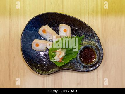 Aburi weißer Fisch auf der Oberseite mit Lachsrogen auf dunkelblauer Keramikplatte serviert geschnitten. Genießen Sie das Omakase-Erlebnis im japanischen Sushi-Restaurant. Stockfoto