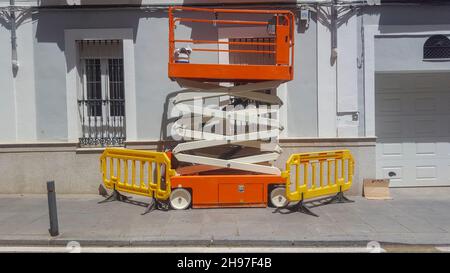 Elektrische mobile Arbeitsbühne. Professionelle Maler Scherenbühne geparkt über Bürgersteig Stockfoto