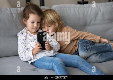 Nette Kinder, die sich mit Online-Lernspielen auf dem Smartphone beschäftigen Stockfoto