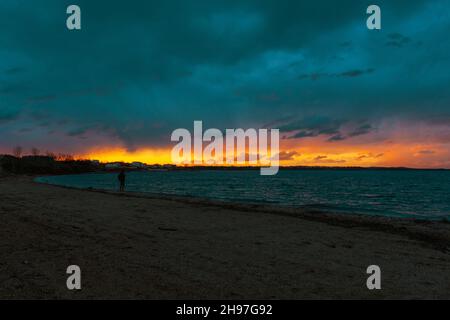 Schöner Sonnenuntergang am Meer. Sonnenlicht scheint durch die Wolken am Horizont. Landschaftlich reizvolle Landschaft. Stockfoto