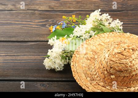 Blumenstrauß in einem Strohhut auf einem hölzernen Hintergrund Stockfoto