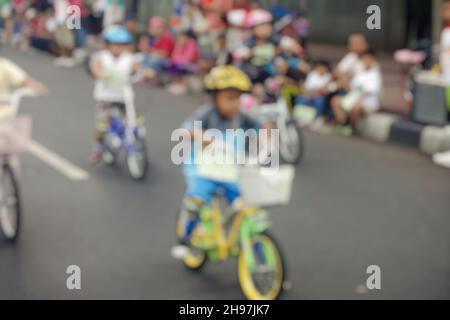 Verschwommene Ansicht des Fahrradrennen von Kindern in Zeitraffer auf der Straße während eines autofreien Tages in Jakarta, Indonesien. Menschenmenge, die im Hintergrund zuschaut. Stockfoto