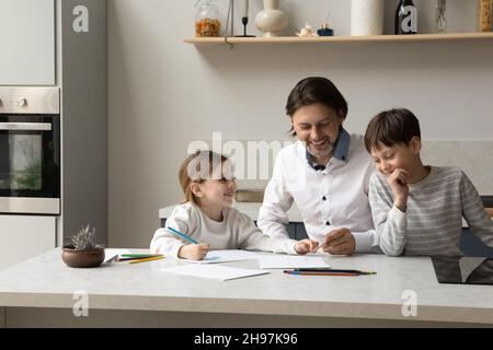 Glücklicher Vater, der mit Kindern zu Hause Bilder zeichnet. Stockfoto