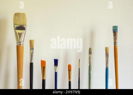 Verschiedene Farbpinsel gegen weiße rustikale Wand. Freier Speicherplatz für Text Stockfoto