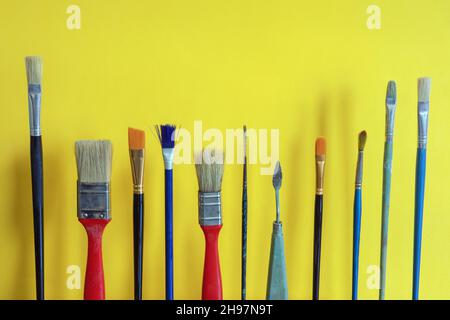 Verschiedene Pinsel auf gelbem Papierhintergrund. Speicherplatz kopieren Stockfoto