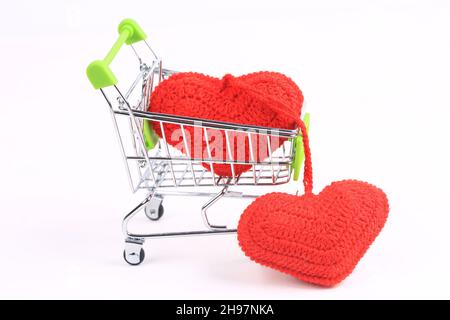 Zwei gestrickte Herzen in einem Warenkorb auf weißem Hintergrund. Kreatives Valentinstags-Konzept Stockfoto