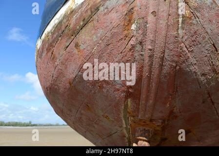 Rumpf eines Bootes, das durch die nachlassende Flut in Barry, Südwales, Großbritannien, hoch und trocken auf dem Sand zurückgelassen wurde Stockfoto