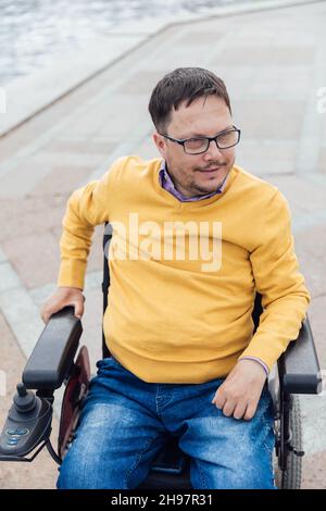 Ein Mann mit Behinderungen im Rollstuhl geht durch die Stadt Stockfoto