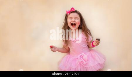 Kind mit Erdbeeren und Schokolade. Mädchen mit roten Beeren und Schokolade in einem rosa Kleid auf gelbem Hintergrund Stockfoto