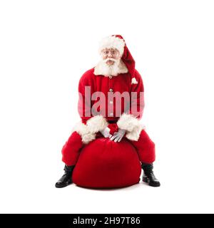 Weihnachtsmann sitzt auf Weihnachten Geschenktüte isoliert auf weißem Hintergrund Stockfoto