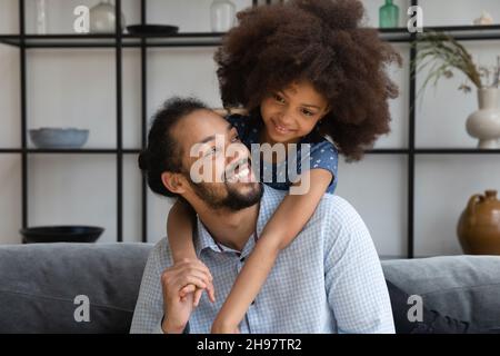 Fröhliche kleine afroamerikanische Mädchen kuscheln liebevollen Vater. Stockfoto