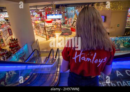 Moskau, Russland. 4th. Dezember 2021 ein Mitarbeiter des Spielwarenladens Hamleys geht die Rolltreppe hinunter zum Laden im Moskauer Kindergeschäft in Lubyanka, Russland Stockfoto