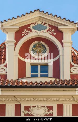 Ein farbenfrohes, historisches Gebäude in der Prager Malá Štupartská mit einem „Auge der Vorsehung“-Symbol, das prominent in einem Baldachin über einem Dachfenster angebracht ist Stockfoto