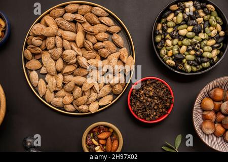 Getrocknete Beas edamame, geschälte Mandeln, getrocknete Früchte und Hafer auf schwarzem Hintergrund Stockfoto