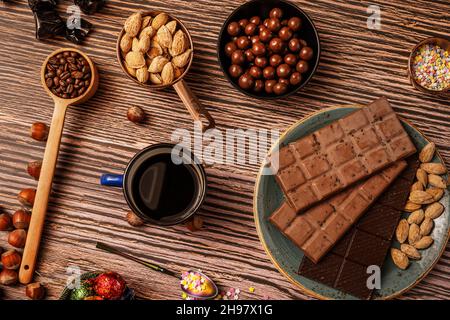 Stillleben mit Schokolade in Bars mit Kaffee und Tee, Schokolade, Haselnüssen und gerösteten gesalzenen Mandeln Stockfoto