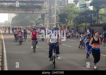 Massen von asiatischen Menschen auf Fahrradtour auf der Straße während autofreien Tag Veranstaltung jeden Morgen Wochenende in Jakarta, Indonesien. Stockfoto
