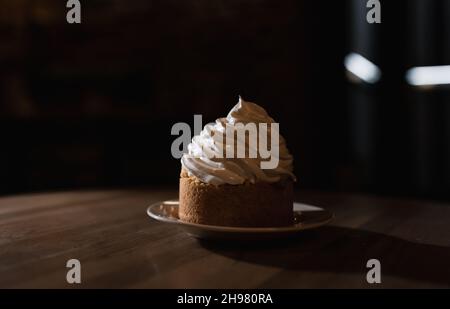 Ein Kuchenkorb mit Proteincreme auf schwarzem Hintergrund. Ein Kuchen auf schwarzem Hintergrund. Stockfoto