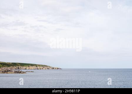 Blick entlang der zerklüfteten Küste nach Westen vom Hafen von Portsoy mit einem kleinen Hummer-Boot aus sammeln Creels. Stockfoto