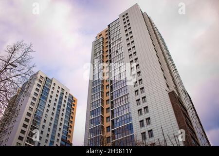 Tscheljabinsk, Russland - Dezember 2021: Moderne Hochhäuser gegen den Himmel mit Wolken. Ansicht von unten nach oben. Stockfoto