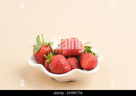Erdbeere, frische, saftige Erdbeeren mit Blättern, serviert in einer kleinen Schüssel. Stockfoto