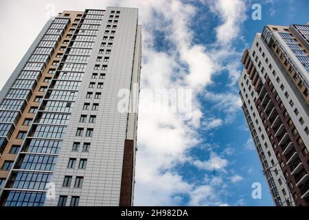 Tscheljabinsk, Russland - Dezember 2021: Hochhäuser vor blauem Himmel mit Wolken. Ansicht von unten nach oben. Geschäftskonzept eines erfolgreichen Industriebogens Stockfoto
