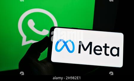 Person, die Smartphone mit Schriftzug des US-Technologieunternehmens Meta Platforms Inc. Auf dem Bildschirm vor dem WhatsApp-Logo hält. Konzentrieren Sie sich auf die Telefonanzeige. Stockfoto