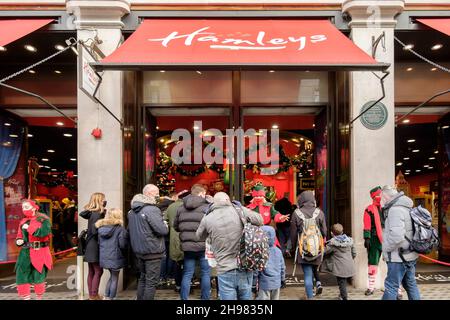 4th. Dezember 2021: Weihnachtseinkäufer im Hamleys-Spielzeugladen in der Regent Street werden von Arbeitern begrüßt, die als Elfen mit Gesichtsbezügen bekleidet sind. Die britische Regierung hat Maßnahmen neu erlassen, die es zu einer rechtlichen Verpflichtung machen, Gesichtsbezüge in Geschäften und öffentlichen Verkehrsmitteln zu tragen, sofern sie nicht vom 30th. November ausgenommen sind, weil sie Bedenken wegen der Omicron-Variante von covid-19 hatte. London, Großbritannien. Stockfoto