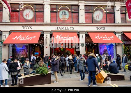 4th. Dezember 2021: Weihnachtseinkäufer im weltberühmten Hamleys Spielzeugladen in der Regent Street, London. Die britische Regierung hat Maßnahmen neu erlassen, die es zu einer rechtlichen Verpflichtung machen, Gesichtsbezüge in Geschäften und öffentlichen Verkehrsmitteln zu tragen, sofern sie nicht vom 30th. November ausgenommen sind, weil sie Bedenken wegen der Omicron-Variante von covid-19 hatte. London, Großbritannien. Stockfoto