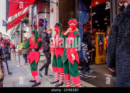 4th. Dezember 2021: Weihnachtseinkäufer im Hamleys-Spielzeugladen in der Regent Street werden von Arbeitern begrüßt, die als Elfen mit Gesichtsbezügen bekleidet sind. Die britische Regierung hat Maßnahmen neu erlassen, die es zu einer rechtlichen Verpflichtung machen, Gesichtsbezüge in Geschäften und im öffentlichen Verkehr zu tragen, sofern sie nicht vom 30th. November ausgenommen sind, weil sie Bedenken wegen der Omicron-Variante von Covid-19 hatte. London, Großbritannien. Stockfoto