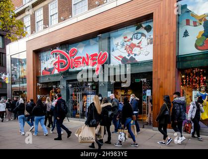 Weihnachtseinkäufer im Disney-Laden in der Londoner Oxford Street. Die britische Regierung hat Maßnahmen neu erlassen, die es zu einer rechtlichen Verpflichtung machen, Gesichtsbezüge in Geschäften und öffentlichen Verkehrsmitteln zu tragen, sofern sie nicht vom 30th. November ausgenommen sind, weil sie Bedenken wegen der Omicron-Variante von covid-19 hatte. Stockfoto