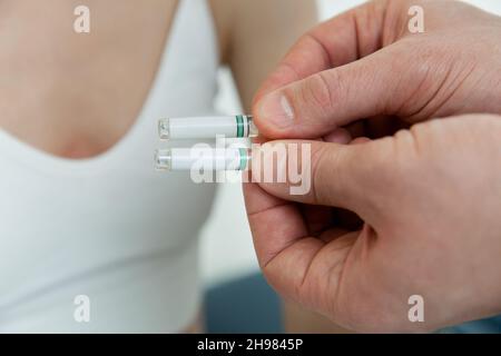 Der Arzt hält kleine Ampullen in den Händen. Nahaufnahme einer kleinen Ampulle mit einem Impfstoff in der Hand des Arztes. Reagenzglas für Allergietest halten. Allergietests Stockfoto