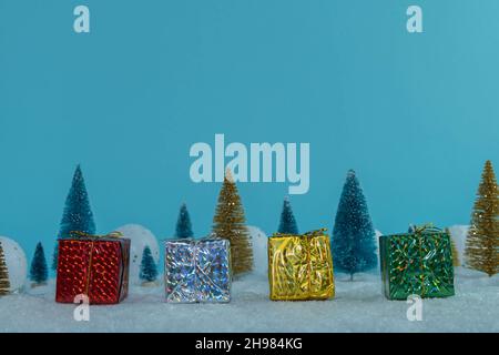 Bunte Geschenke auf dem Hintergrund des Winterwaldes. Sie stehen im Schnee. Frohe Weihnachten. Frohes neues Jahr Stockfoto